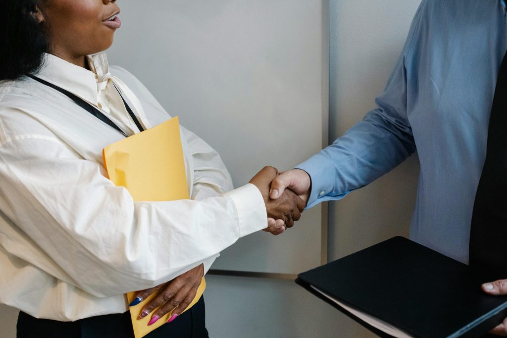 Two professionals shaking hands in an office setting, symbolizing agreement.